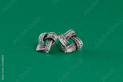 Silver earrings isolated on green background