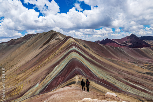 Tourists couple stand and look afar at Rainbow Mountains, Cusco, Peru.