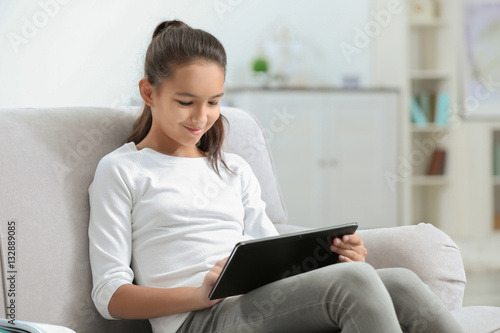 Cute girl sitting on sofa w...