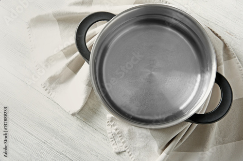 Stainless saucepan and napkin on white wooden table