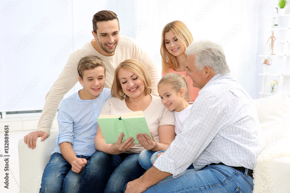Happy family reading book while sitting on sofa in living room