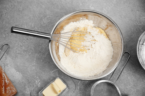Bowl with flour, dough and whisk on kitchen table