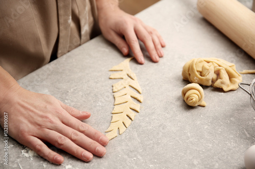 Young woman working with dough in kitchen, closeup