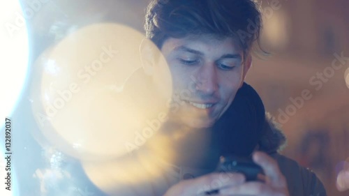 Portrait of young man using his mobile phone at night. Young man outdoors with mobile phone on the street over Christmas decoration.