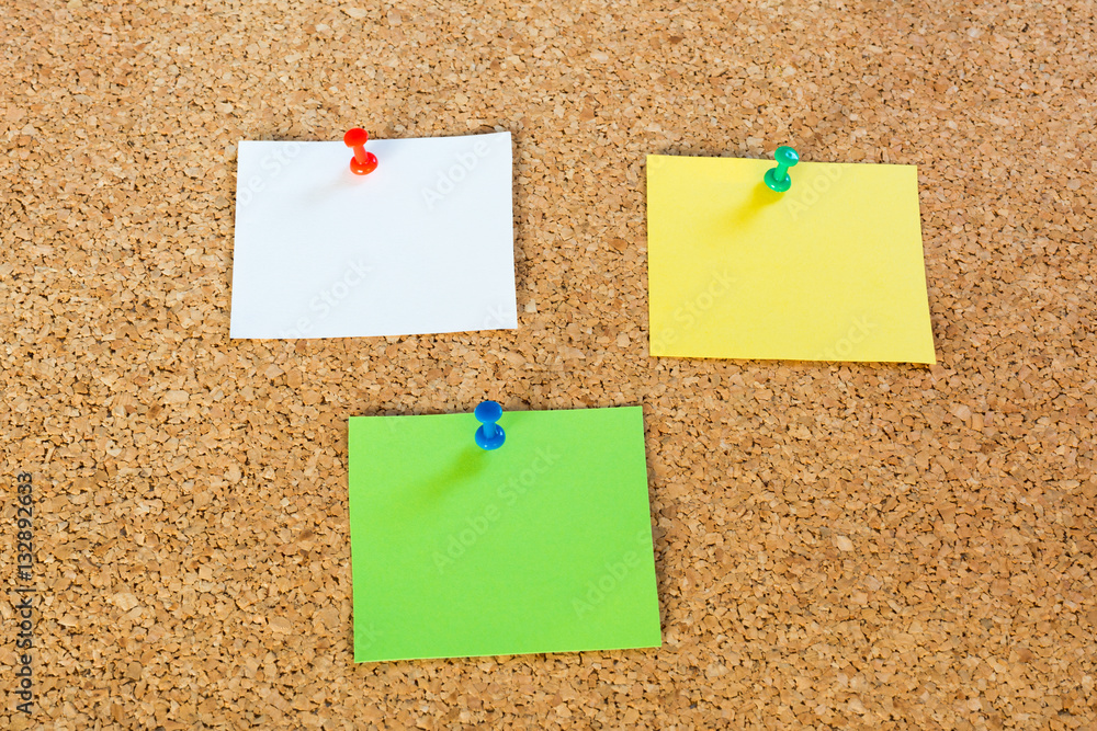 Thumbtack pins and notepaper on pinboard Thumbtack pins and notepaper on pinboard