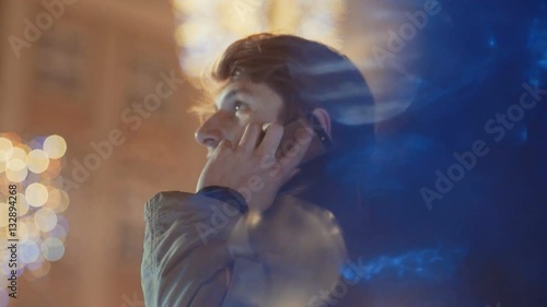 Young man outdoors talking on mobile phone on the street with Christmas decoration.
