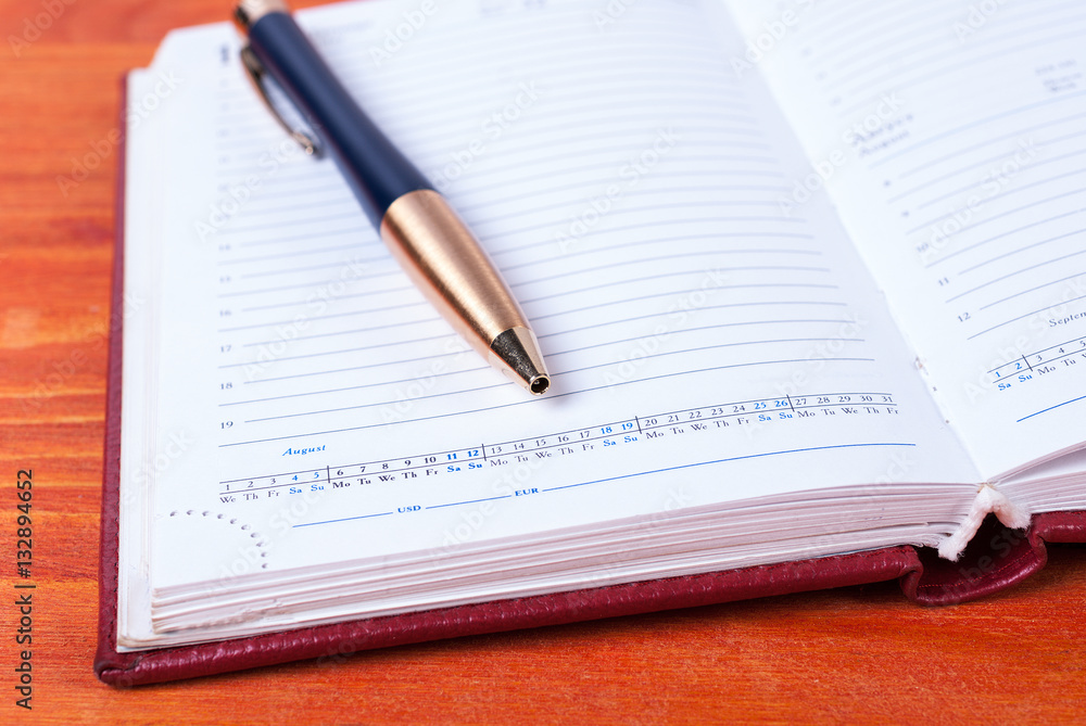 Open diary with pen lying on a wooden table Open diary with pen lying on a wooden table