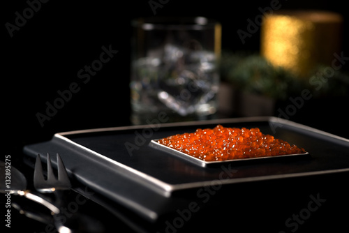 red caviar lies on a square ceramic stylish black plate