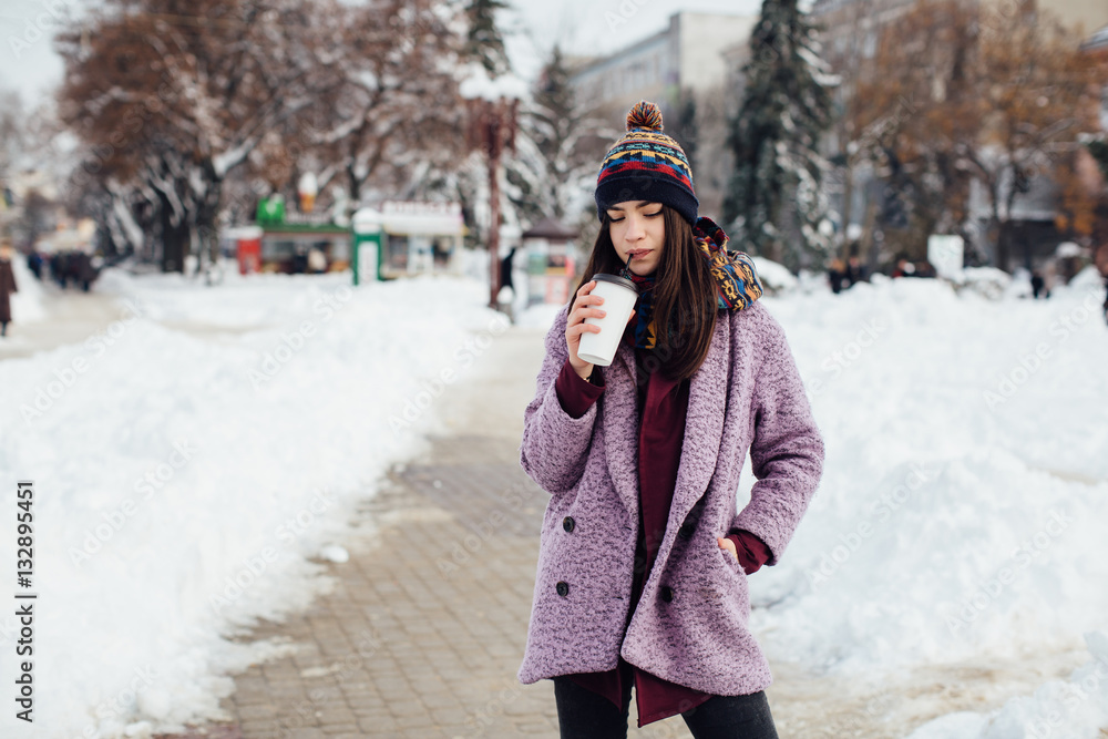 Girl walking the winter street and drinking coffee