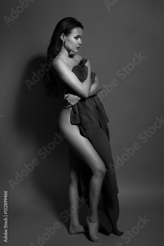 Black and white photo of a seductive brunette girl in studio. Sexy topless woman. Monochrome image.