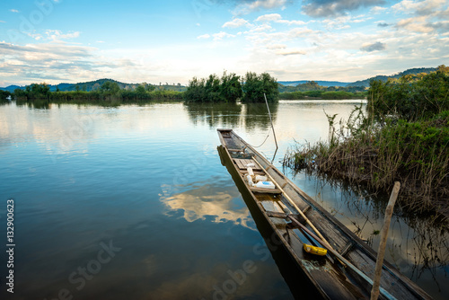 Fototapeta Naklejka Na Ścianę i Meble -  wooden rowboat in the calm water of lake at beautiful sunset
