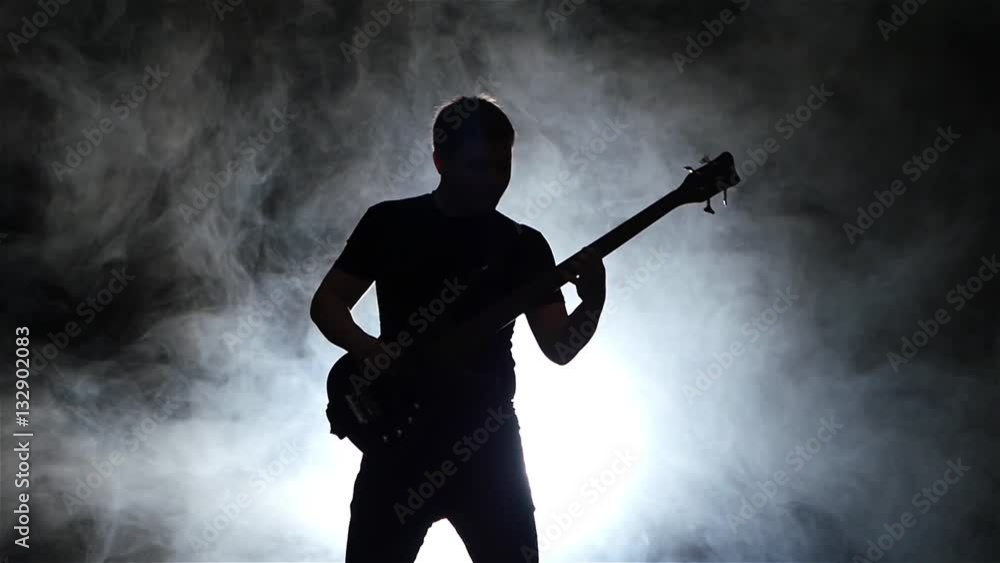 Slow motion. Silhouette bass guitarist man in smoke. Black background Slow motion. Silhouette bass guitarist man in smoke. Black background