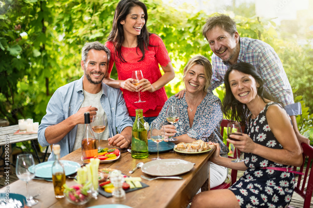 Group of friends gathered around a table on a summer terrace Group of friends gathered around a table on a summer terrace