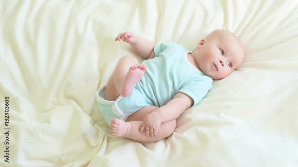 Little baby in a light blue bodysuit holding his feet. Little baby in a light blue bodysuit holding his feet.