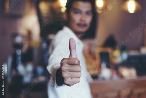 Businessman showing thumbs up in the coffee shop.