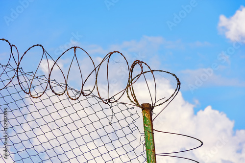 Barbed wire protection fence with blue sky at the bottom