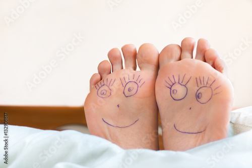 Pair of female feet with smiling faces on it.
