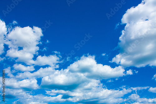 Blue sky background with clouds in bright sunny summer day.