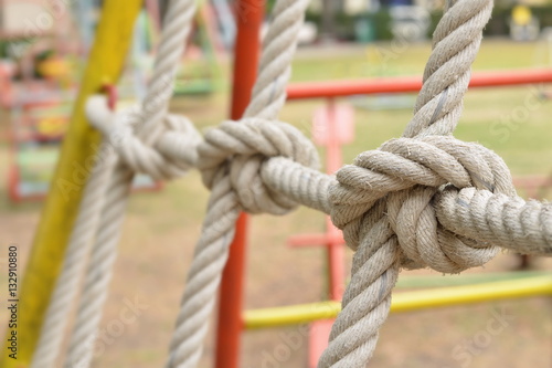 Close-up of rope knot line tied together with playground background,as a symbol for trust, teamwork or collaboration
