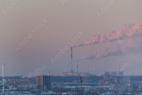 Industrial landscape with smoking pipes at winter sunset, global warming concept © KONSTANTIN SHISHKIN