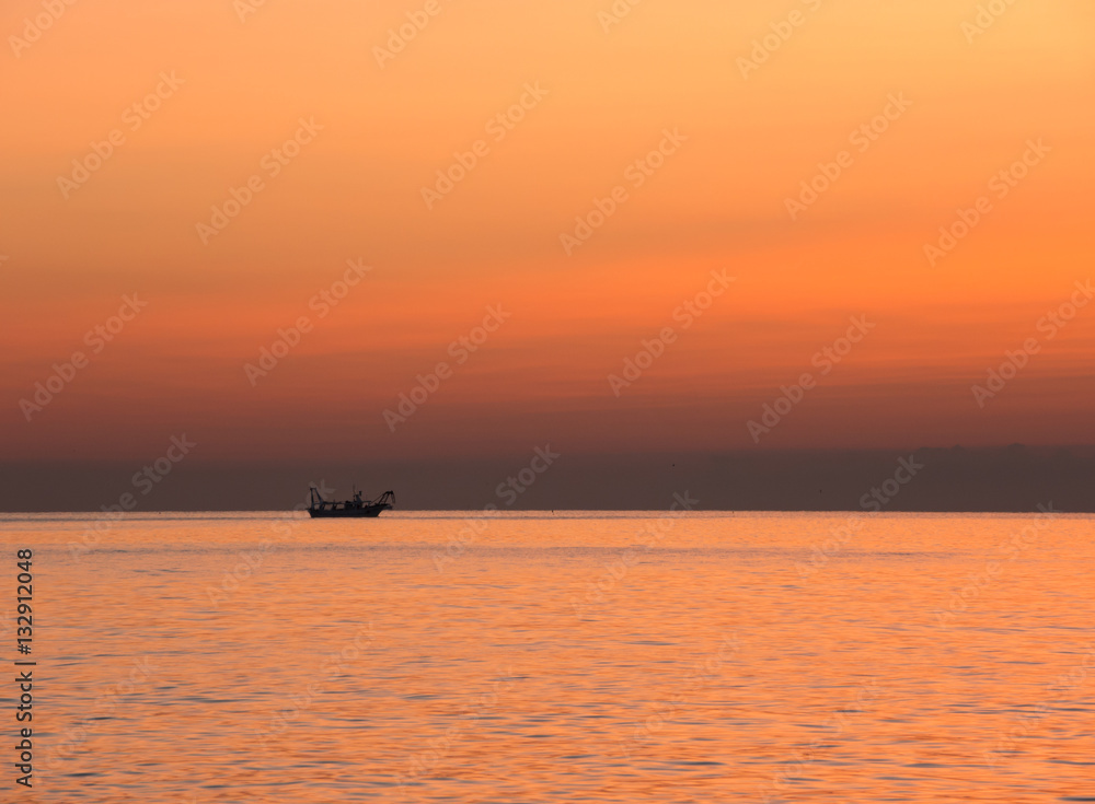 Fishing boats pull their nets at the sunrise. Adriatic cost. Emilia Romagna. Italy.