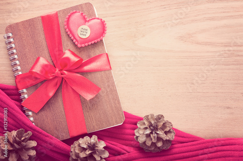 notebook wrapped with red ribbon and red felt hearts on wooden t