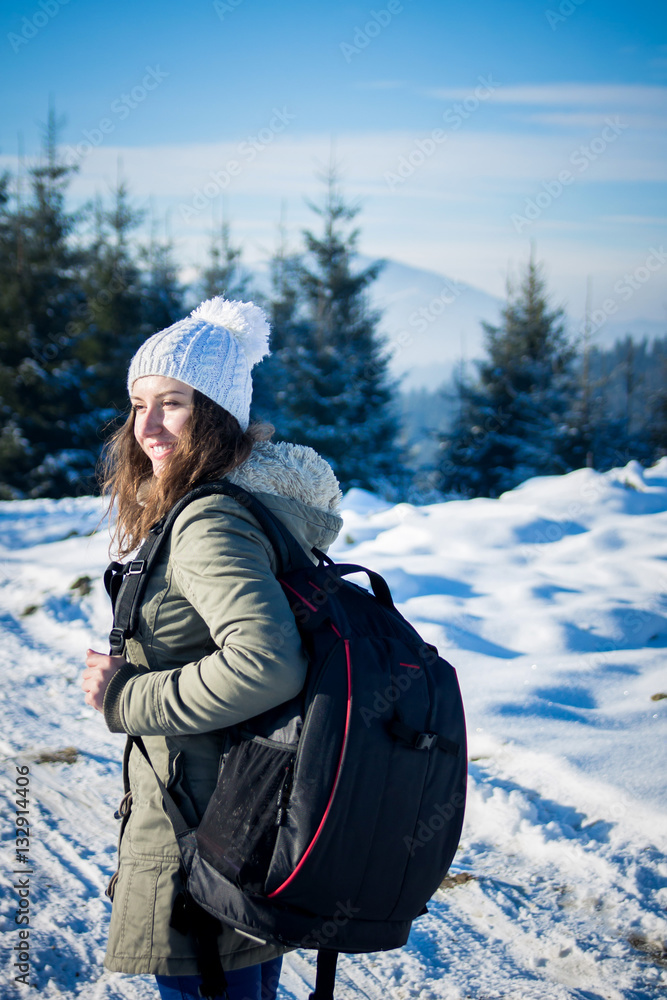 Fototapeta premium Girl backpacker walking in winter mountain forest