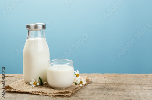 Tela A bottle of rustic milk and glass of milk on a wooden table on a