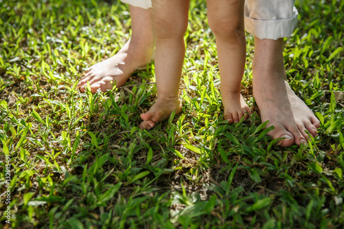 Closeup portrait of a mother teaching baby to walk outdoors.