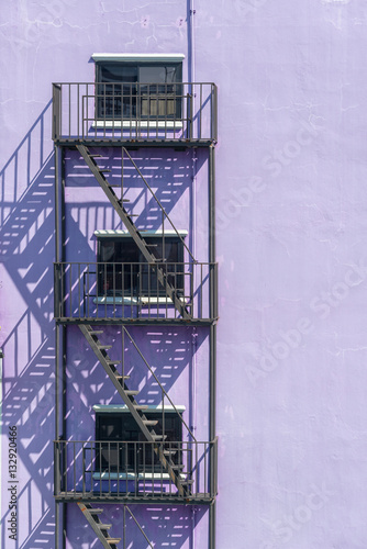 Obraz na plátně Fire escape metal on light Purple Vintage stone wall outside bui