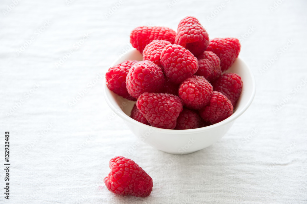 Fresh raspberries in a big red ceramic bowl on a white table. Fresh raspberries in a big red ceramic bowl on a white table.