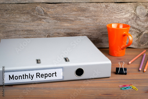 Monthly Report. Folder, Coffee Mug, colored pencils on wooden office desk.