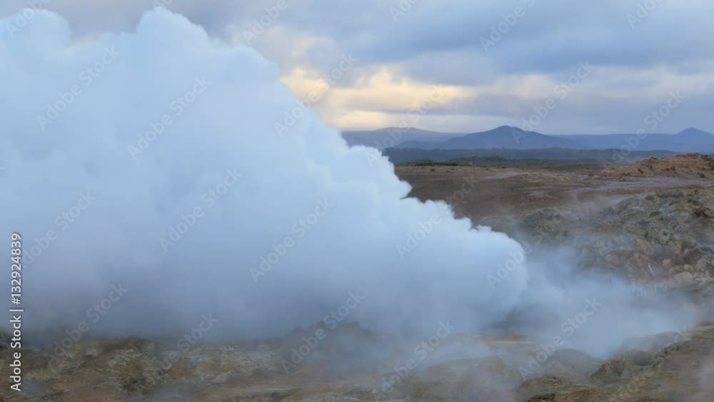 huge white puffs of steam are pulling out from earth, picturesque colorful ground, mountain, sky huge white puffs of steam are pulling out from earth, picturesque colorful ground, mountain, sky