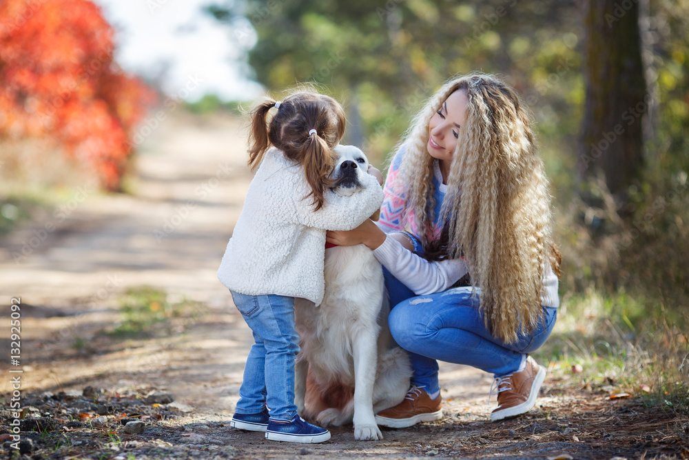 Family portrait of young blonde woman with long wavy hair and her little daughter,walking together with the dog breed Golden Retriever in a beautiful autumn Park Family portrait of young blonde woman with long wavy hair and her little daughter,walking together with the dog breed Golden Retriever in a beautiful autumn Park