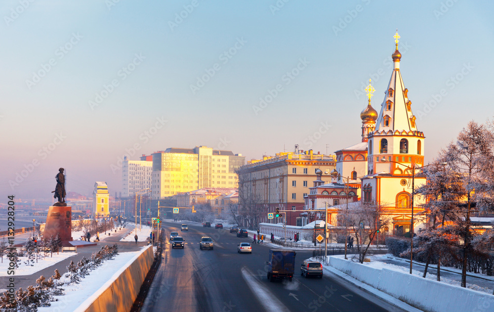 Obraz premium Siberia. Irkutsk. The view from the pedestrian bridge to the Cathedral of the Epiphany, monument to the Founder of the city and the Lower Embankment of Angara River at winter evening