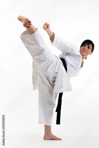 Young black belt karate fighter training hight kick . Isolated woman portrait on white background