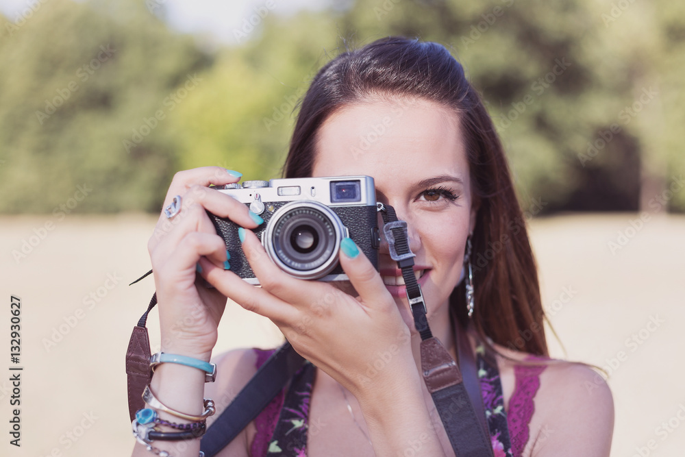 beautiful brown hair girl while shooting a picture with her camera at park in a sunny day. summer portrait with old color filter effect beautiful brown hair girl while shooting a picture with her camera at park in a sunny day. summer portrait with old color filter effect