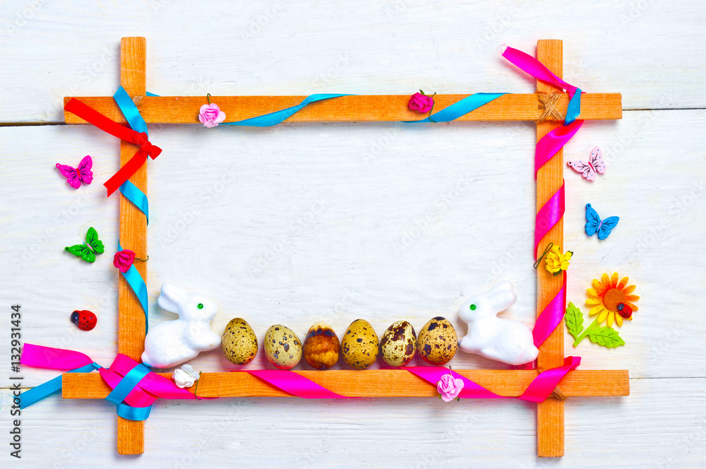 Fototapeta premium Easter eggs in the frame with ribbons on a white wooden background