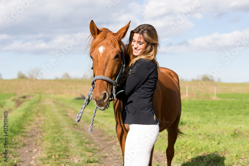 Beautiful young girl in uniform competition hugs her horse : outdoors portrait on sunny day