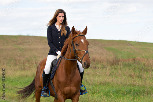 Beautiful young girl in uniform competition ride her brown horse : outdoors portrait on sunny day