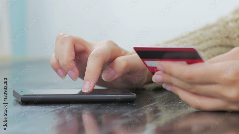 Young woman buying goods from the internet and entering number security code from credit card on smartphone. Online, technology and internet concept Young woman buying goods from the internet and entering number security code from credit card on smartphone. Online, technology and internet concept