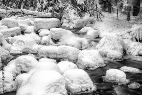 Long exposure of frozen stream in winter forest. Jalovecka valley in Slovakia. Black and white photography photo