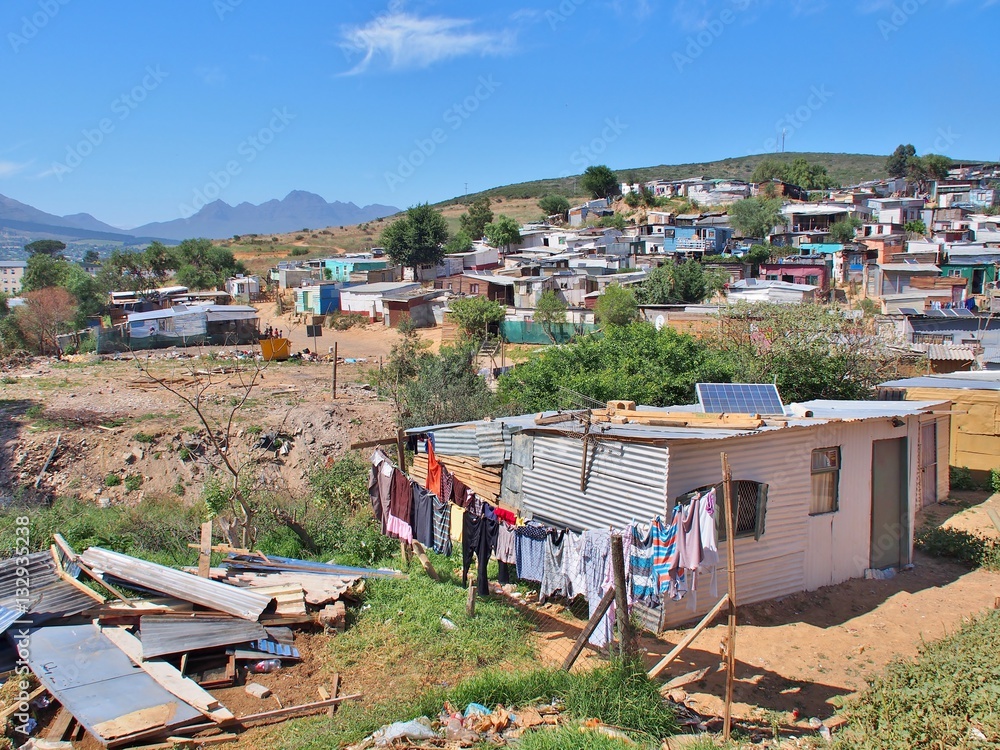 Informal settlement - Enkanini with mountain and blue sky on the outskirts  of Stellenbosch, Western Cape province, South Africa. Many shacks in  Enkanini have solar panels for access to electricity. Stock-Foto