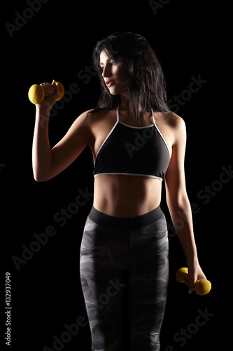 Portrait of a young brunette sporty fitness woman with dumbbell