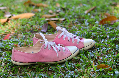 Pink sneakers on the floor in the garden. 