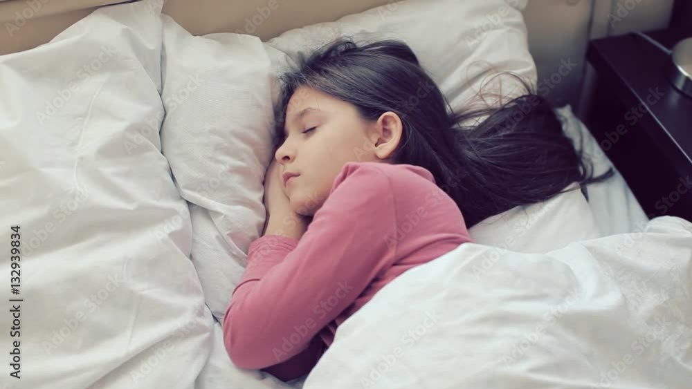 Little girl sleeps. Girl is sleeping. Little girl dressed in pajamas asleep in bed in the children's room. Little girl sleeps. Girl is sleeping. Little girl dressed in pajamas asleep in bed in the children's room.