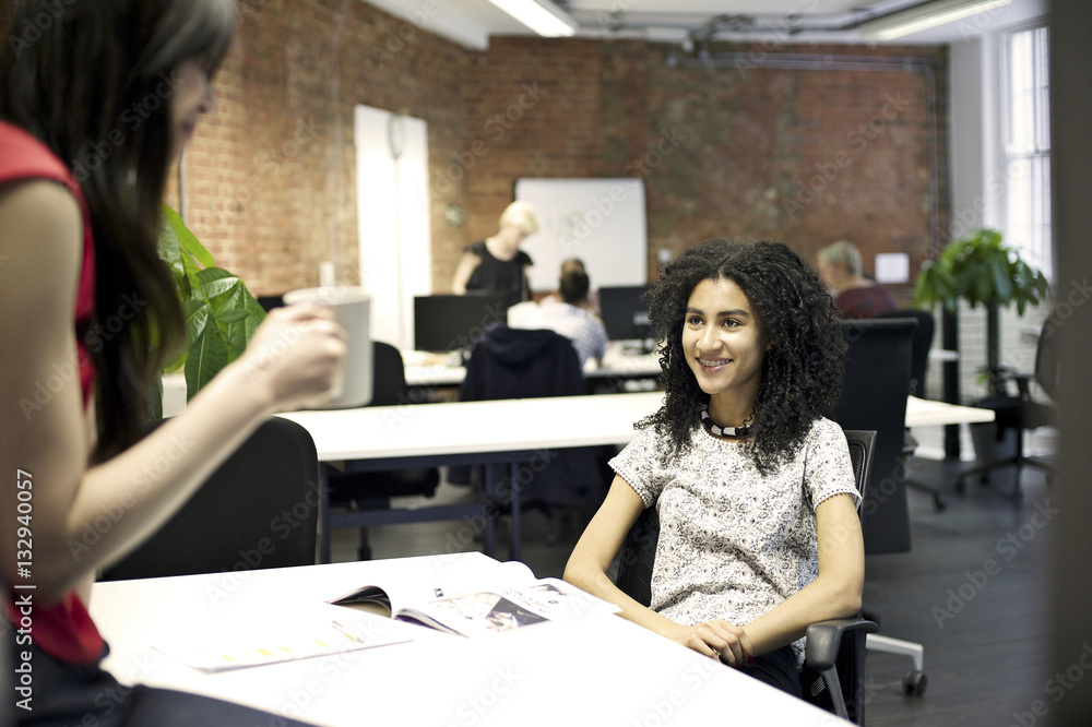 Young mixed race businesswoman smiling in an informal office meeting Young mixed race businesswoman smiling in an informal office meeting