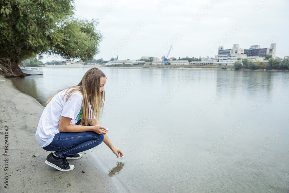 Teenage girl taking a water sample out of river Teenage girl taking a water sample out of river