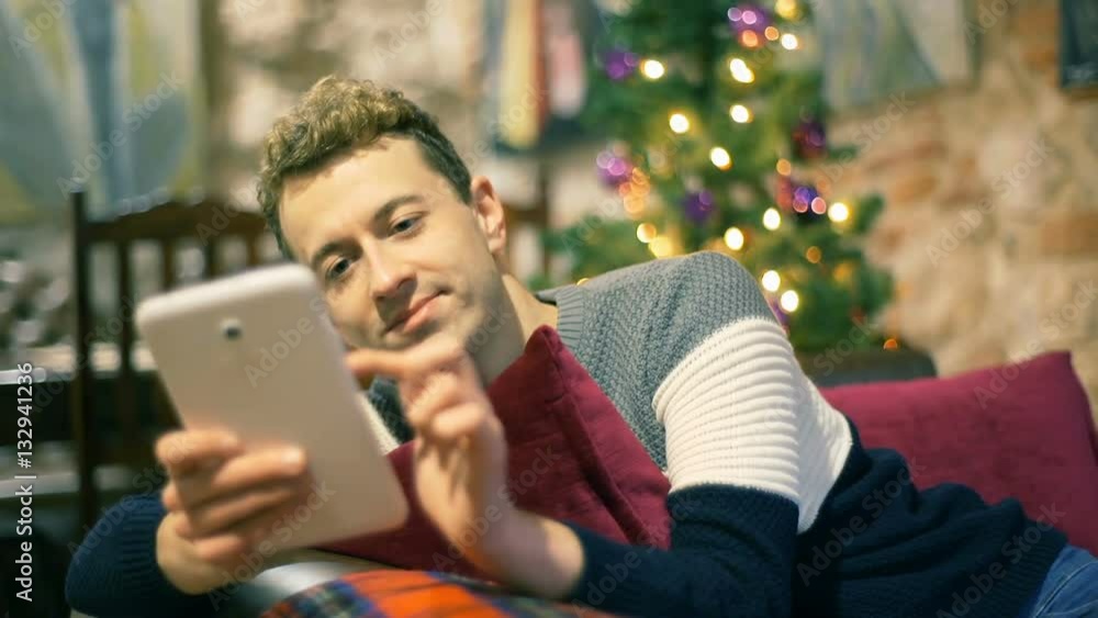 Man browsing internet on tablet and smiling to the camera in the festive cafe, steadycam shot
Man browsing internet on tablet and smiling to the camera in the festive cafe, steadycam shot