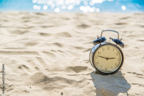 old retro clock on sand beach over blurred of tropical blue sea